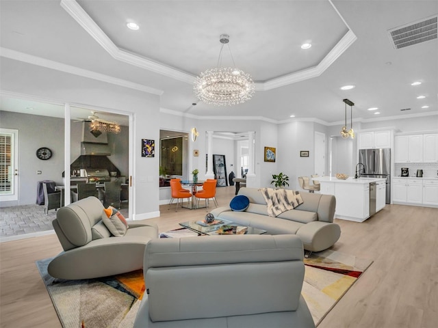 living room with a tray ceiling, ornamental molding, and light wood-type flooring