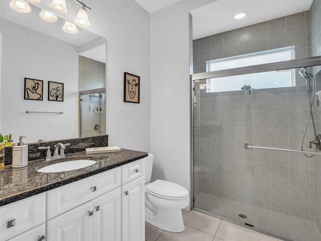 bathroom featuring toilet, a shower with shower door, tile patterned floors, and vanity