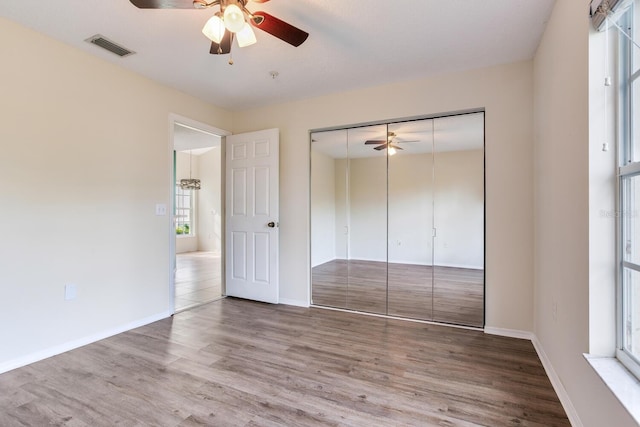 unfurnished bedroom with ceiling fan, a closet, and hardwood / wood-style floors