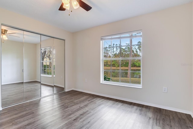 unfurnished bedroom with ceiling fan, a closet, and dark hardwood / wood-style flooring