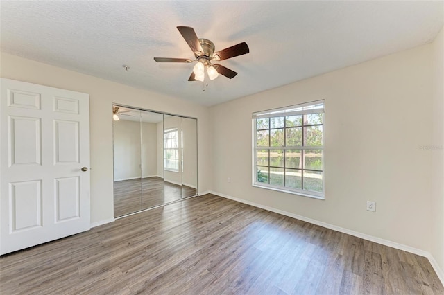 unfurnished bedroom featuring ceiling fan, hardwood / wood-style floors, a closet, and a textured ceiling