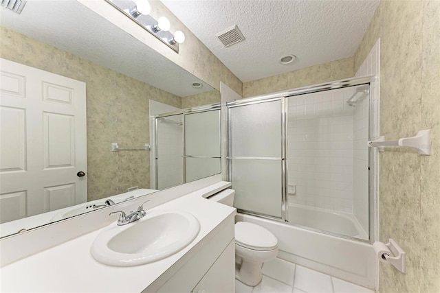 full bathroom featuring toilet, vanity, tile patterned floors, a textured ceiling, and shower / bath combination with glass door