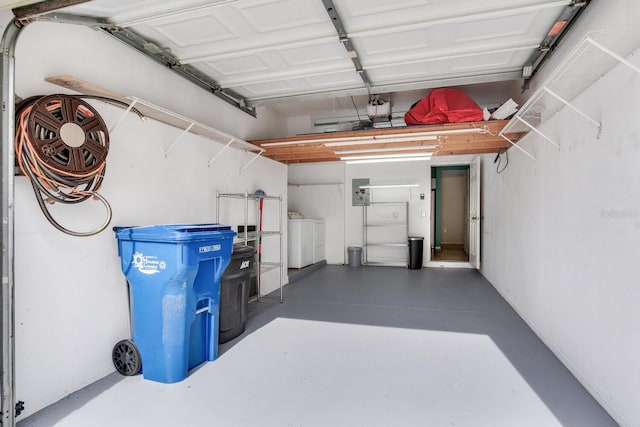 garage featuring washer and dryer, electric panel, and a garage door opener