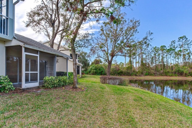 view of yard with a sunroom and a water view