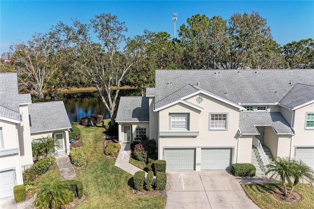 view of front of home featuring a front yard, a garage, and a water view