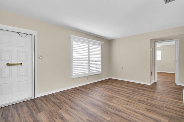 unfurnished room featuring dark wood-type flooring and a healthy amount of sunlight