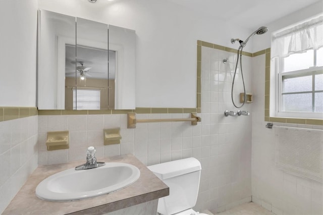 bathroom featuring sink, tile walls, toilet, ceiling fan, and tiled shower