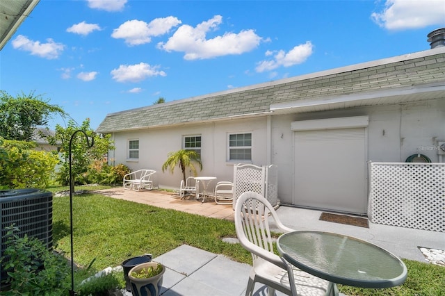 rear view of property featuring central AC unit, a lawn, and a patio