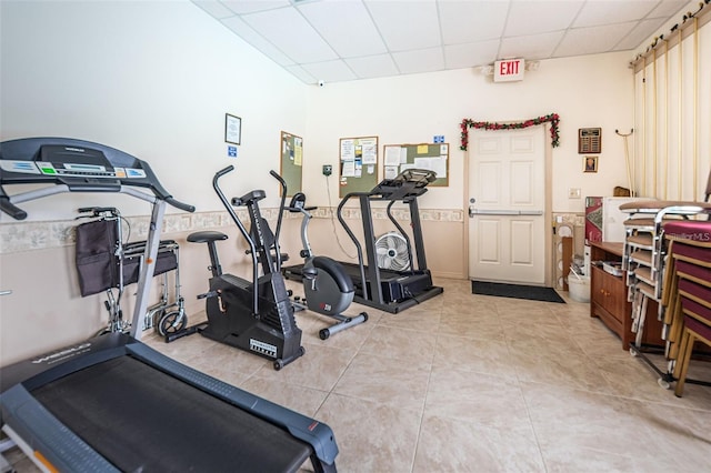 exercise area with a paneled ceiling and light tile patterned flooring