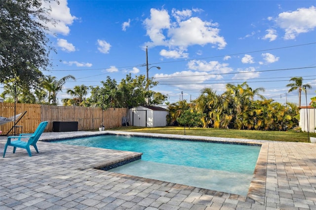 view of pool with a patio, a yard, and a storage shed