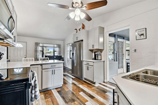 kitchen with gray cabinetry, stainless steel appliances, lofted ceiling, and dark wood-type flooring