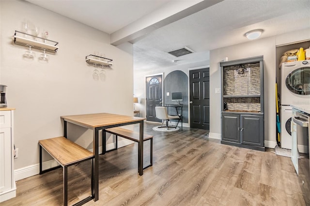 dining area featuring stacked washer and clothes dryer and light wood-type flooring