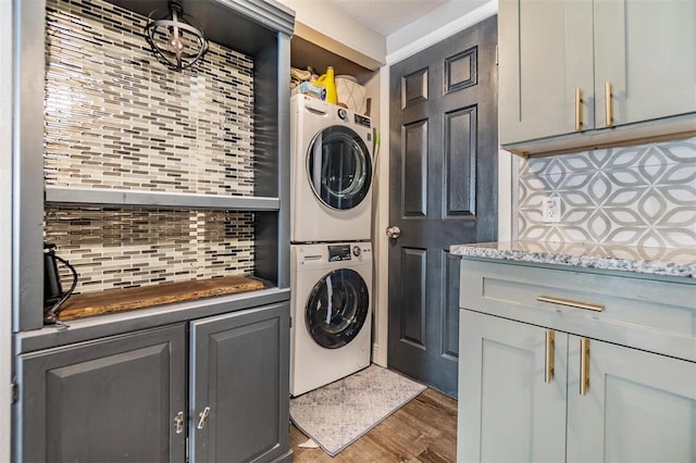 laundry room featuring stacked washer and clothes dryer and hardwood / wood-style flooring