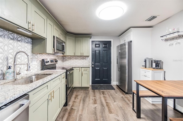 kitchen featuring sink, green cabinets, backsplash, and appliances with stainless steel finishes