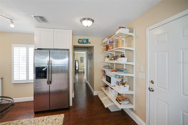 kitchen with stainless steel fridge, white cabinetry, and dark wood-type flooring