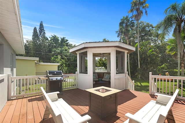 deck featuring a grill, an outdoor fire pit, and a sunroom