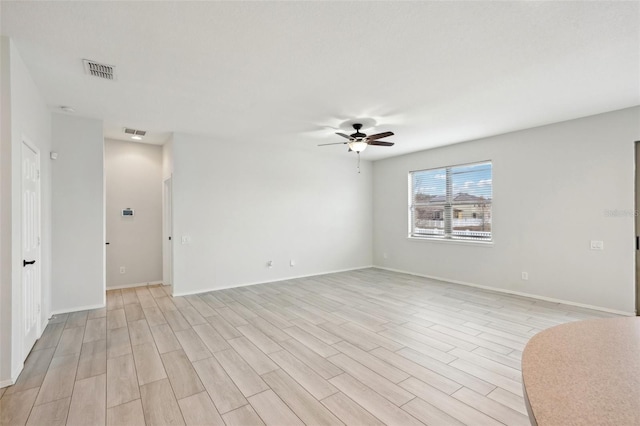 empty room with ceiling fan and light hardwood / wood-style flooring