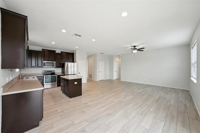 kitchen with a center island, stainless steel appliances, light hardwood / wood-style floors, ceiling fan, and sink