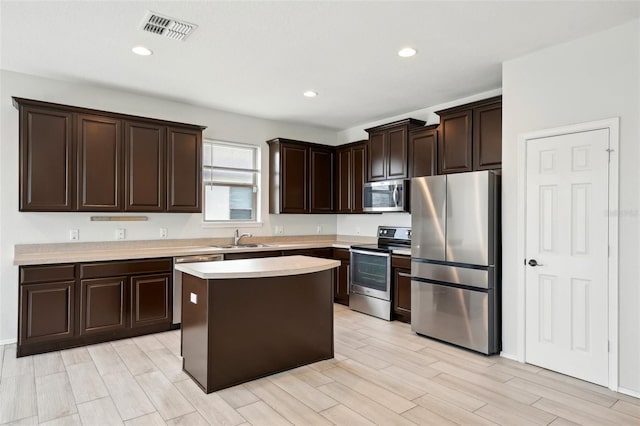 kitchen featuring sink, stainless steel appliances, light hardwood / wood-style floors, a kitchen island, and dark brown cabinetry