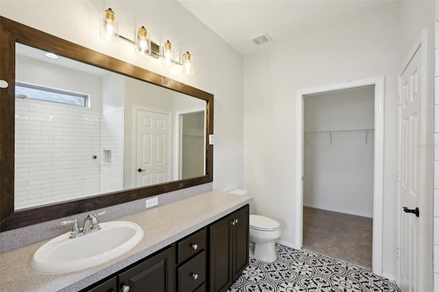 bathroom with toilet, a shower, vanity, and tile patterned floors