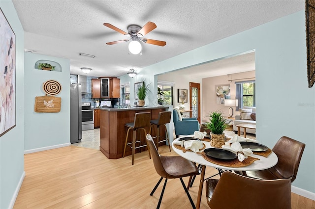 dining room with ceiling fan, light wood-type flooring, sink, and a textured ceiling