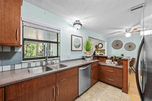 kitchen with dishwasher, light tile patterned floors, ceiling fan, a textured ceiling, and sink