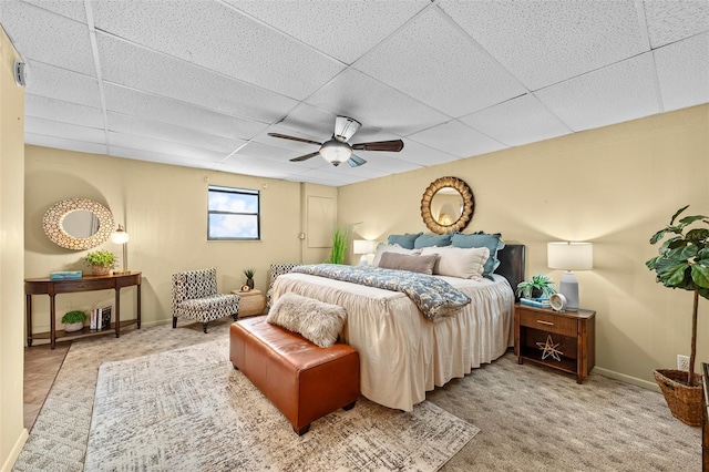 carpeted bedroom with a paneled ceiling and ceiling fan