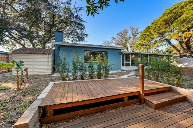 wooden deck featuring a sunroom and a storage unit