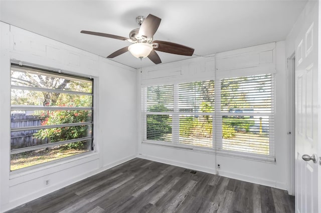 empty room with dark hardwood / wood-style flooring, ceiling fan, and a healthy amount of sunlight