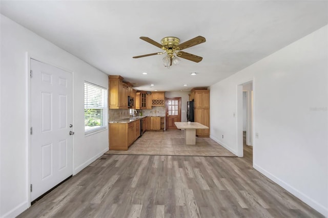 kitchen featuring black refrigerator, light hardwood / wood-style floors, ceiling fan, sink, and tasteful backsplash