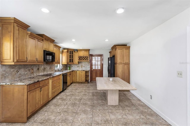 kitchen featuring black appliances, sink, light stone countertops, and tasteful backsplash