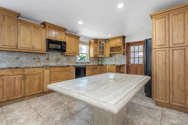 kitchen with light stone counters, light tile patterned floors, black appliances, a kitchen island, and backsplash