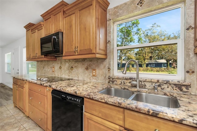 kitchen featuring light stone counters, black appliances, decorative backsplash, and sink