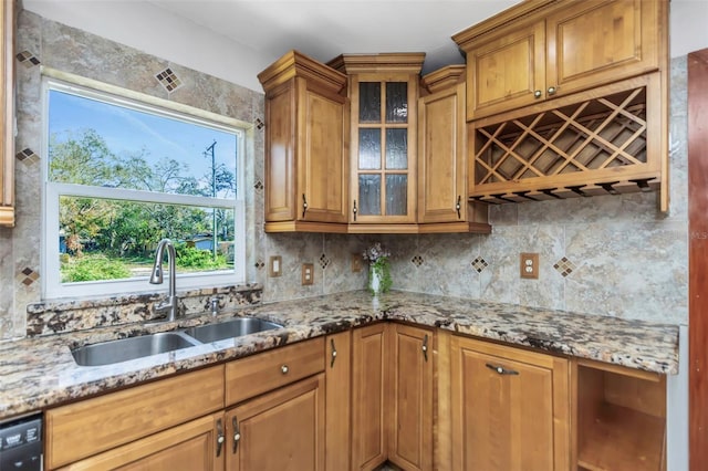 kitchen with sink, tasteful backsplash, black dishwasher, and light stone countertops