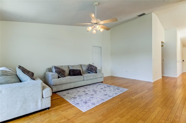 living room with vaulted ceiling, a textured ceiling, ceiling fan, and light hardwood / wood-style flooring