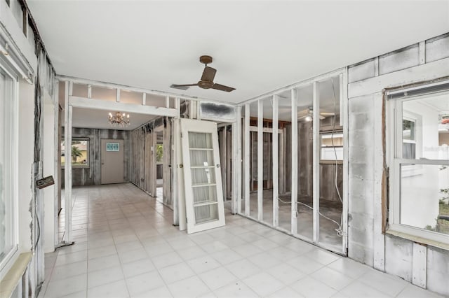 unfurnished sunroom featuring ceiling fan with notable chandelier