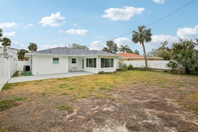 rear view of house with central AC, a patio area, and a lawn