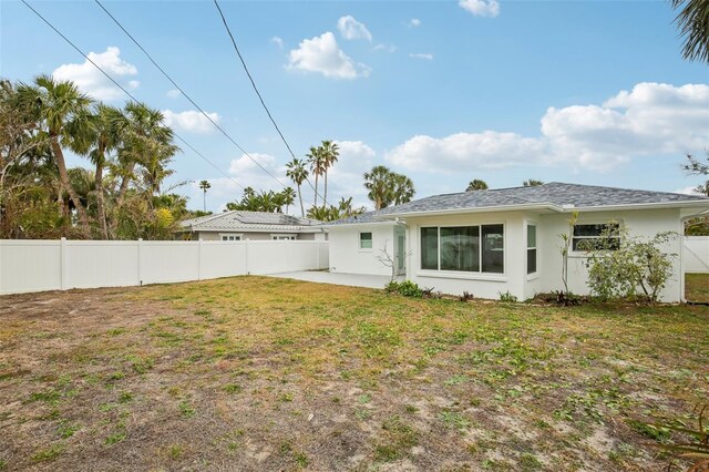 back of property with a lawn and a patio