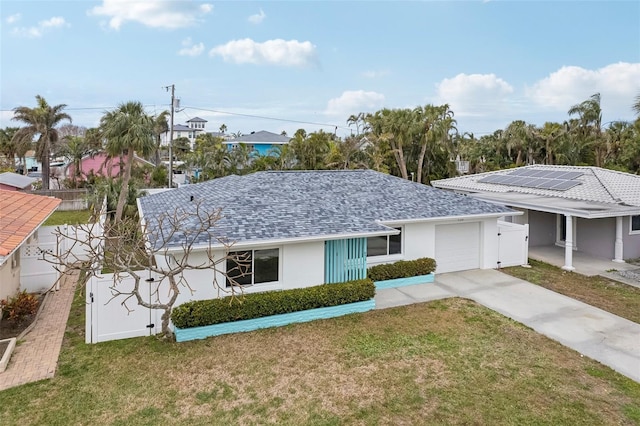 view of front of property featuring a garage, a front yard, and solar panels