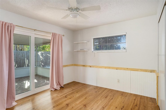 unfurnished room featuring a textured ceiling, light wood-type flooring, and plenty of natural light