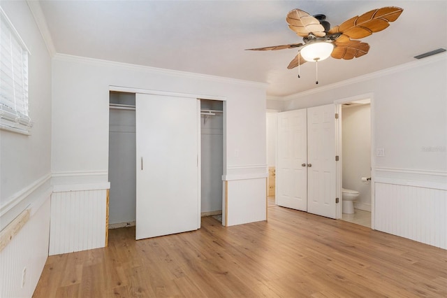 unfurnished bedroom with connected bathroom, a closet, light wood-type flooring, ceiling fan, and ornamental molding