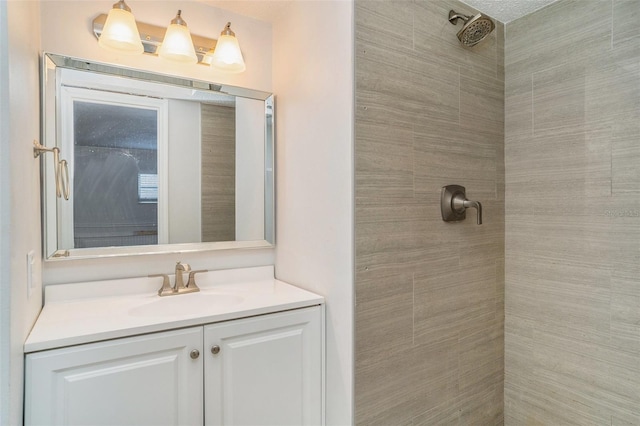 bathroom with tiled shower and vanity