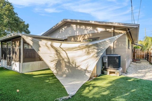 view of side of property featuring central air condition unit, a yard, and a sunroom