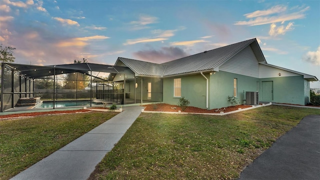 view of front facade featuring central AC, glass enclosure, and a lawn