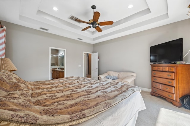 bedroom featuring ceiling fan, ensuite bathroom, and a raised ceiling