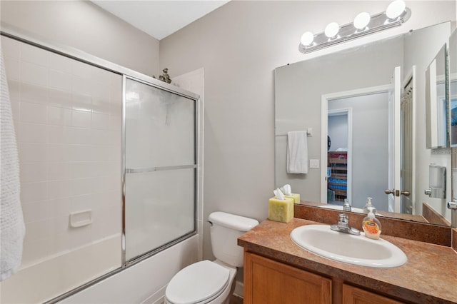 full bathroom featuring toilet, bath / shower combo with glass door, and vanity