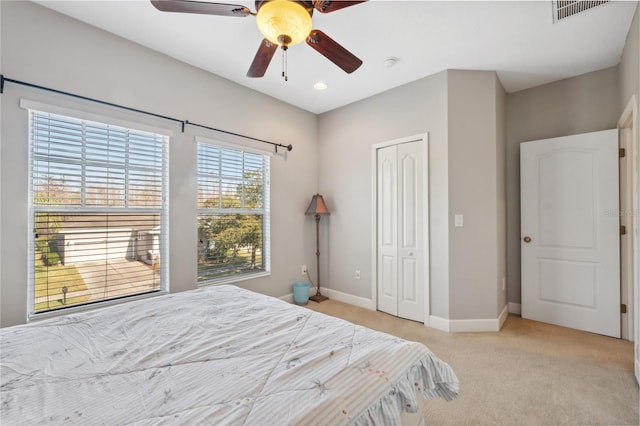 bedroom with ceiling fan, a closet, and light carpet