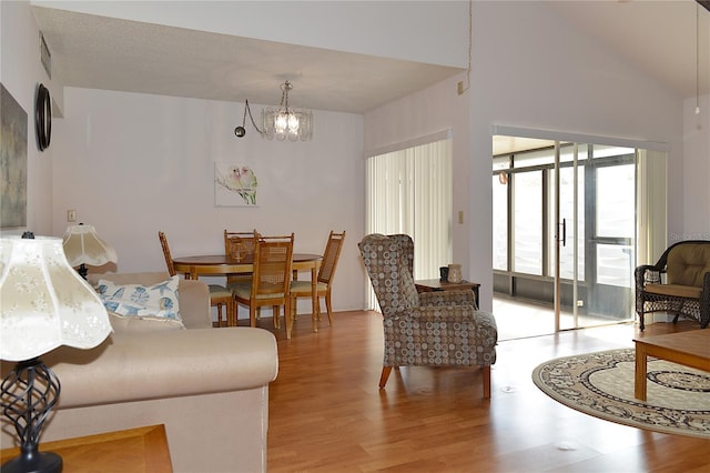 living room featuring light hardwood / wood-style flooring, a chandelier, and vaulted ceiling