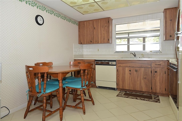 kitchen with light tile patterned floors, backsplash, sink, and white dishwasher