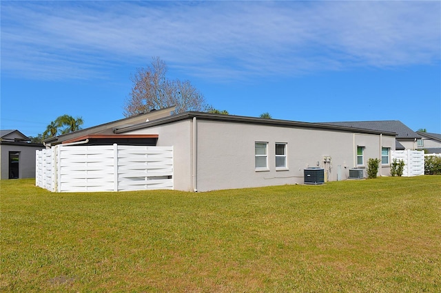 view of property exterior featuring central air condition unit and a lawn